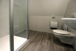 Ein modernes Badezimmer mit Duschkabine aus Glas, Toilette und Handtrockner.