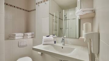 A modern bathroom with a white sink, a toilet, a shower, and a mirror.