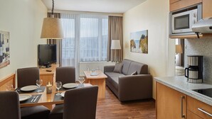 A hotel room with a dining area, a sofa, a TV, a microwave, and a coffee maker. - Appartements im Freizeitpark Weissenhauser Strand (Wangels)