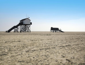A beach with two wooden structures, one with a staircase and another with a flat roof. - Apartment in St.peter-ording mit Terrasse (St. Peter-Ording)