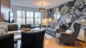 Una sala de estar moderna con un sofá, un sillón, una mesa de comedor y un ventanal grande.