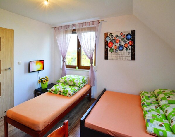 A small, cozy room with two single beds, a TV, a window with curtains, and a wall art piece. - Apartment Close to the Beach, Playground (Mielno)