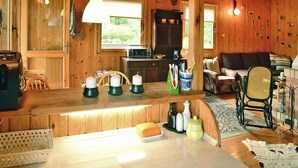 Ein Holzblockhaus-Interieur mit Küchenzeile, Esstisch und Sitzecke.