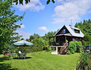 A rustic cabin with a porch, surrounded by a well-maintained lawn and trees. - Holiday Home Near Gowidlinskie Lake (Sierakowice)