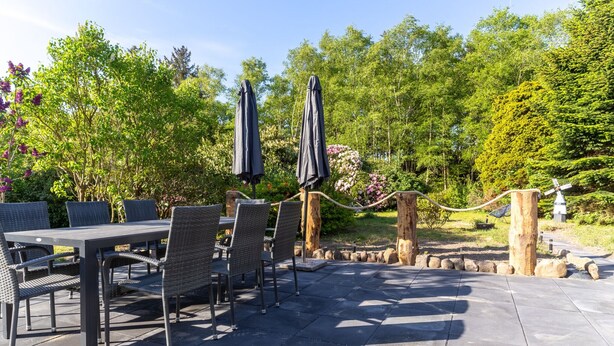 An outdoor patio with a table and chairs, surrounded by greenery and a decorative rope barrier. - Comfortable Holiday Apartment in St. Peter Ording (St. Peter-Ording)