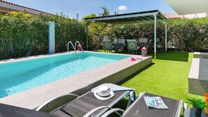 A swimming pool with lounge chairs and a covered patio area.
