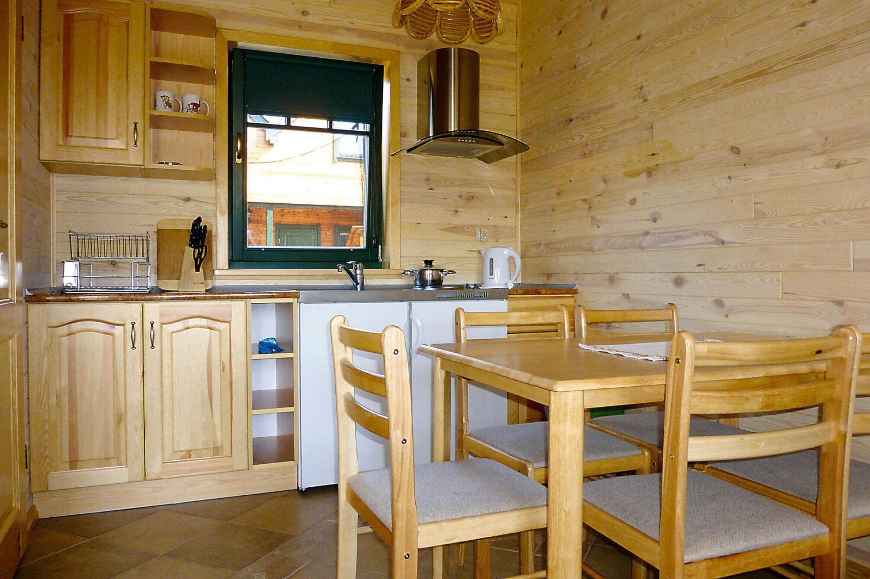 A wooden interior with a kitchen area, including cabinets, a sink, and a dining table with chairs.