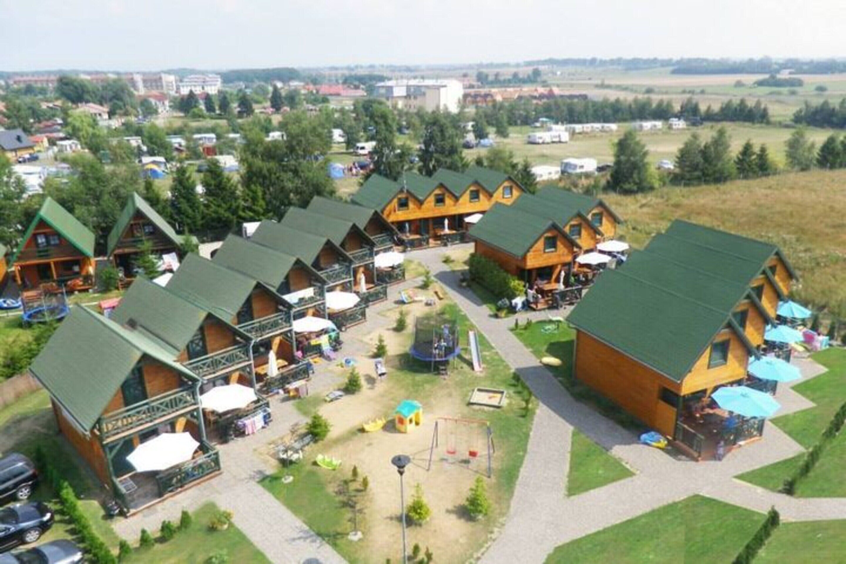 A row of log cabin-style cabins with outdoor seating areas and a playground.