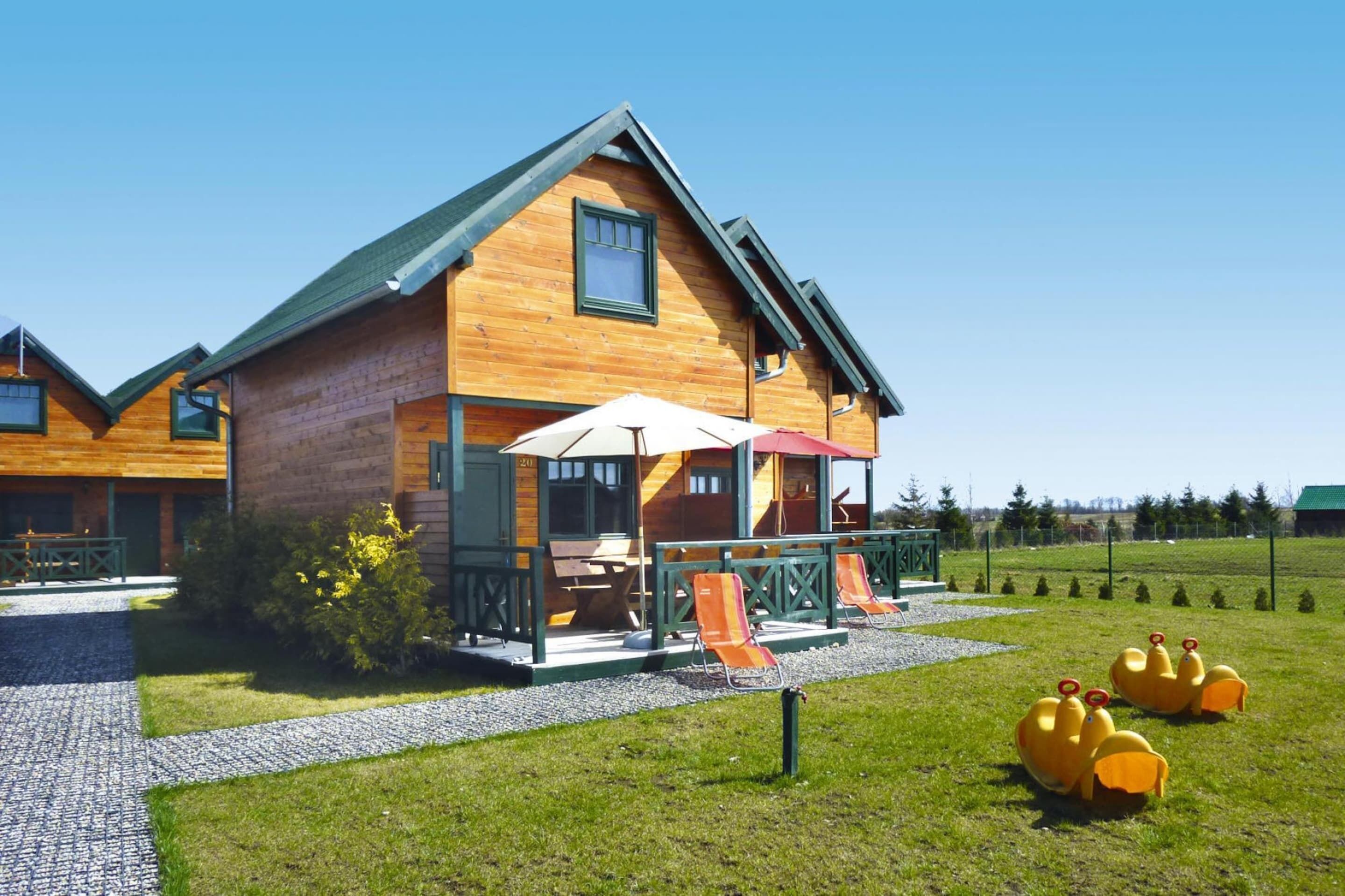 Een houten hut met veranda, buitenzitplaatsen en een glijbaan.