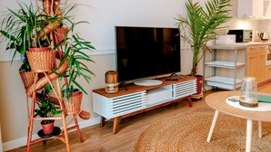 A modern living room with a TV, wooden cabinet, wicker plant stands, and a round table. - Beautiful Apartment Very Close to the Beach (Rewal)