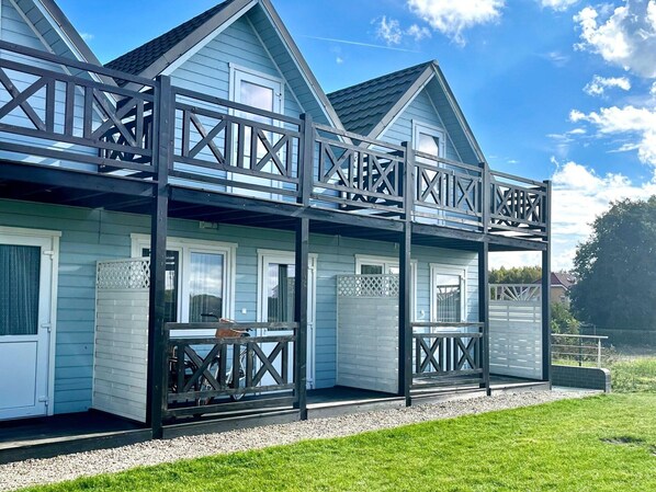 Ein zweistöckiges Haus mit Balkon und überdachter Veranda.