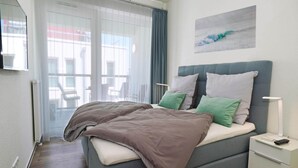 Un dormitorio moderno con una cama, mesitas de noche y vistas a través de una ventana.