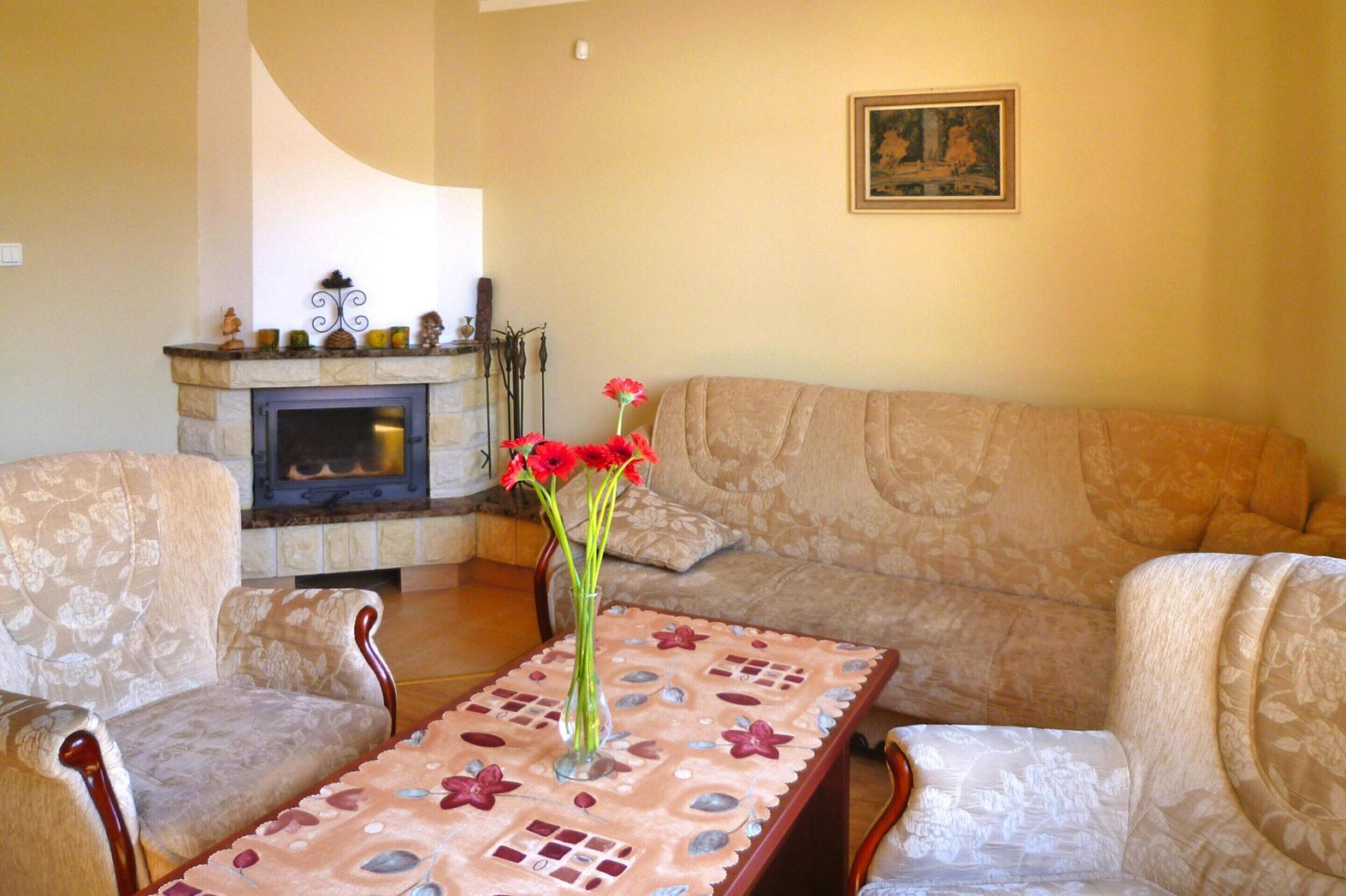 Un salon avec une cheminée, un canapé et une table sur laquelle est posé un vase de fleurs.