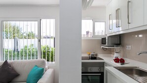 A modern kitchen with white cabinets, a microwave, a stove, and a sink.