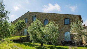 A stone building with a garden, a patio with chairs, and a stone pathway. - Borgo Collelungo Apartments, Montaione (Montaione)