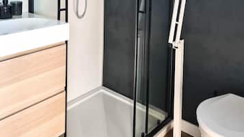 A modern bathroom with a glass shower enclosure, a white toilet, and a wooden vanity.