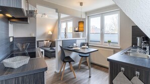 Et moderne køkken med spiseplads, indbygget komfur og et vindue, der giver naturligt lys.