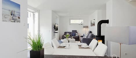 A modern living room with a dining area, a fireplace, and a television.