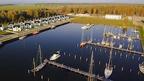 Un port de plaisance doté de plusieurs quais et abritant de nombreux bateaux, entouré d’une rangée de bâtiments blancs aux toits sombres, qui semblent être des immeubles résidentiels ou commerciaux.