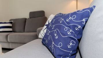 A grey sofa with a blue pillow featuring white anchor patterns.