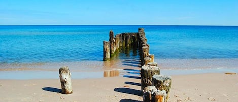 A sandy beach with a wooden structure extending into the water.