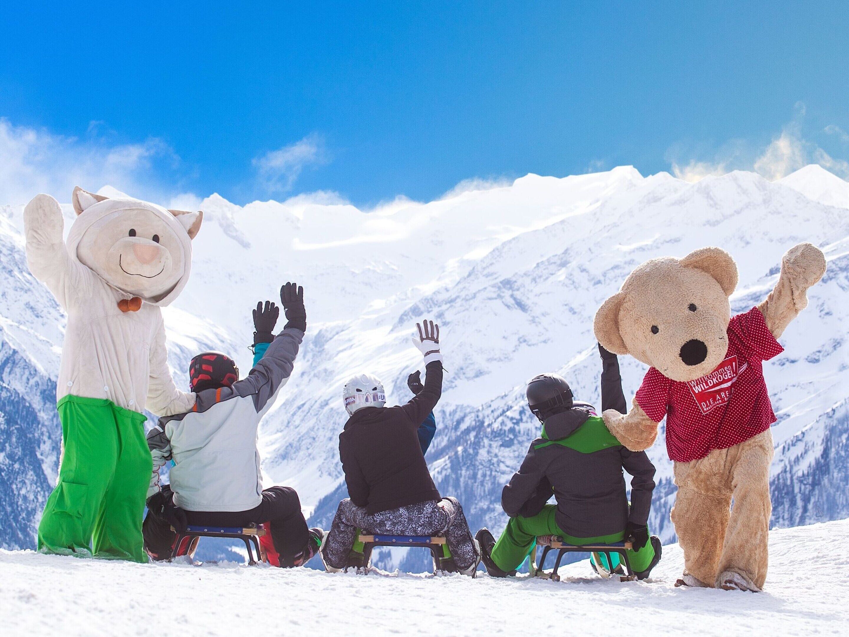 Eine Gruppe von Personen auf einem verschneiten Berg, mit einer Bärenmaskotte.
