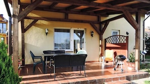 An outdoor patio with a wooden pergola, a table with chairs, and a barbecue grill. - Holiday Home in Kolczewo by the Lake (gmina Wolin)