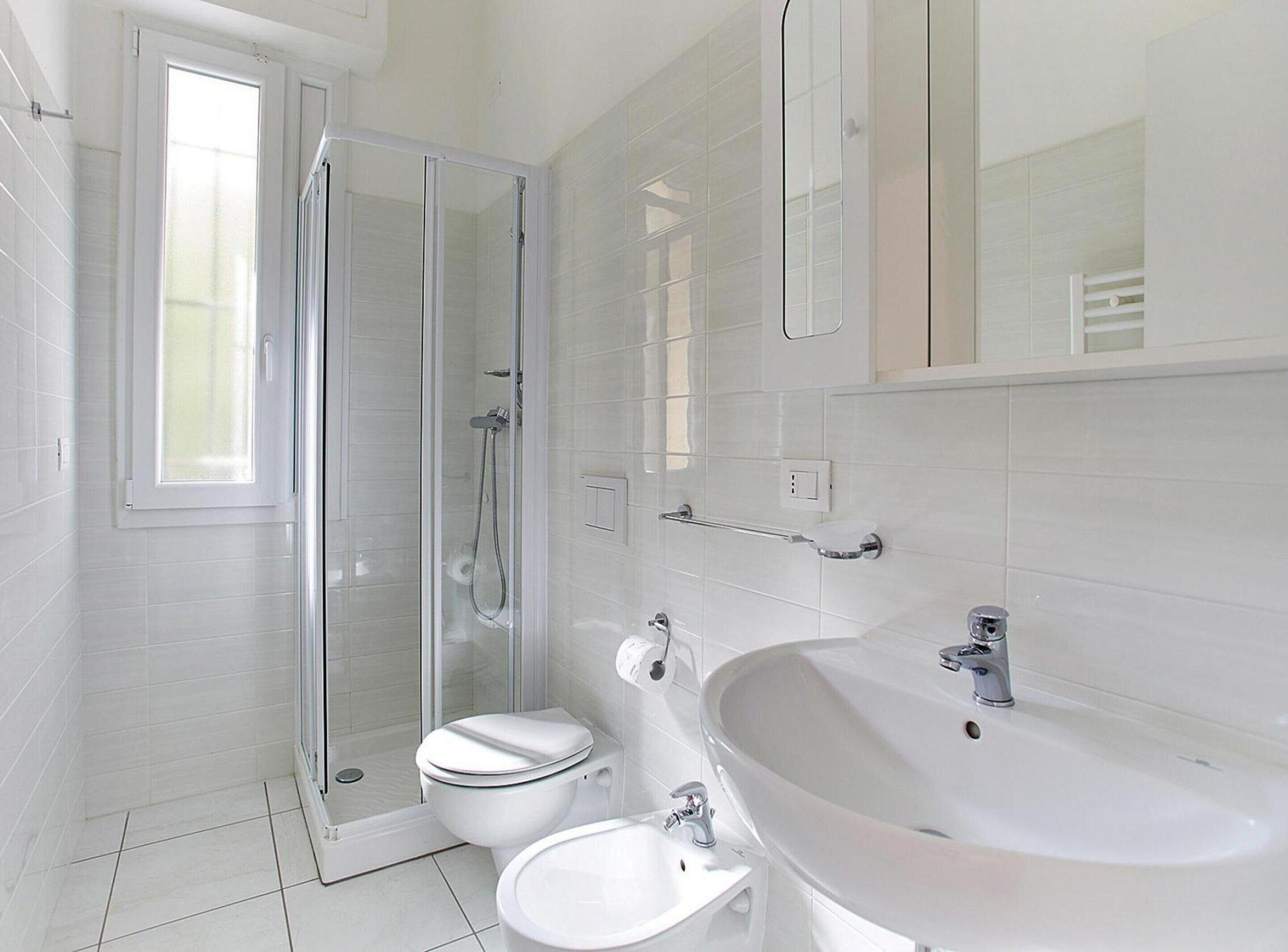 A modern bathroom with a glass-enclosed shower, a toilet, and a sink.