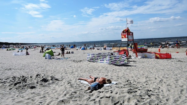 A beach with people sunbathing, tents, and a lifeguard tower. - Holiday House in Dziwnowek Near Sea and Lake (Kamien Pomorski)
