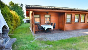 Une cabane en rondins de bois dotée d’un patio comprenant une table et des chaises.