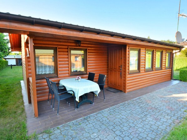 A log cabin with a patio area featuring a table and chairs, a door, and windows. - Single-story Holiday Home Close to the Beach (gmina Manowo)