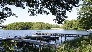 Ein Steg am See mit Booten und einer Bank.