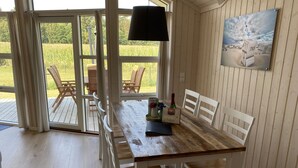 Ein Essbereich mit einem Holztisch, weißen Stühlen, einer Champagnerflasche und einem Bild an der Wand.