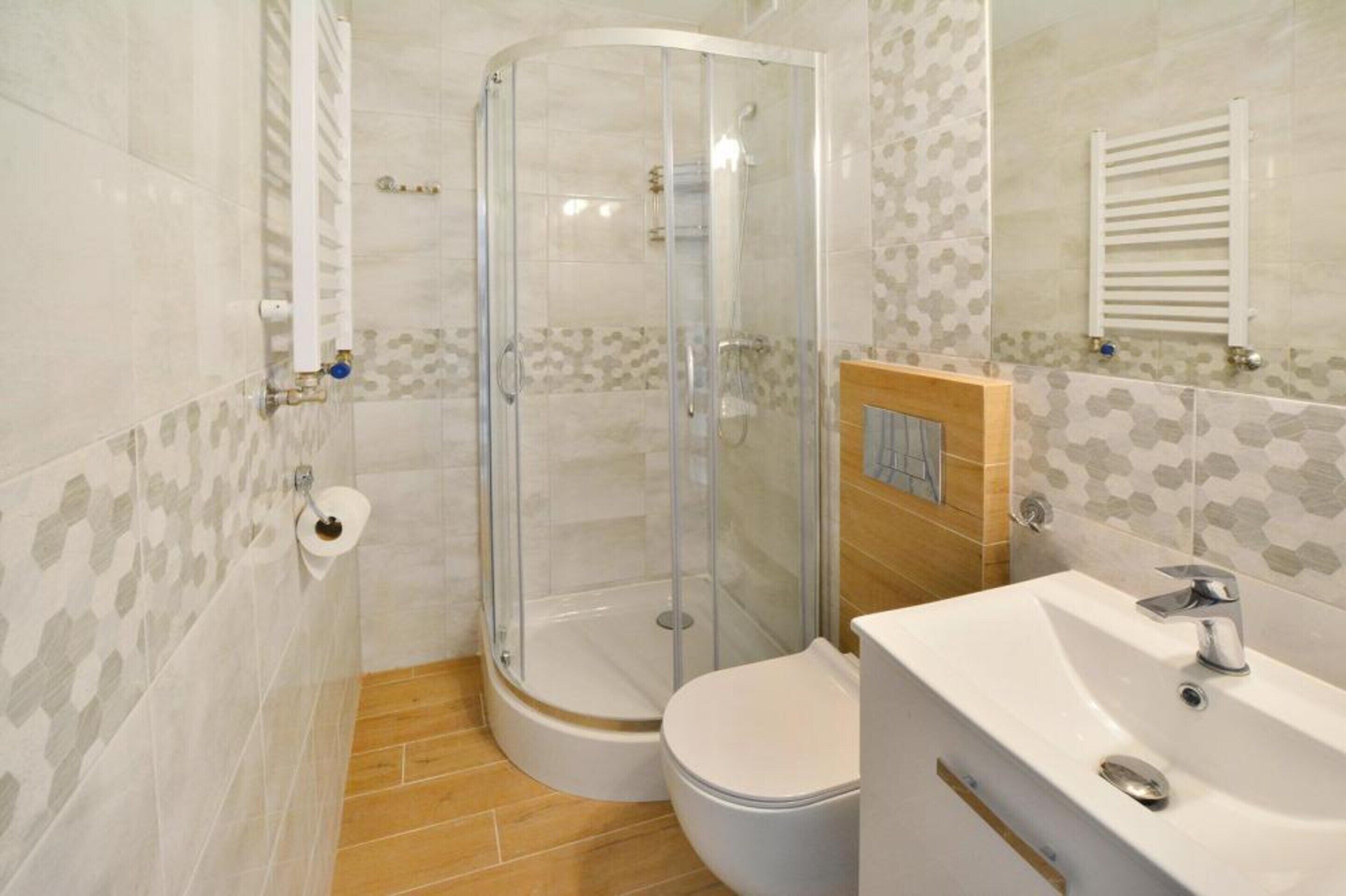 Un baño con ducha acristalada, inodoro y lavabo con espejo.