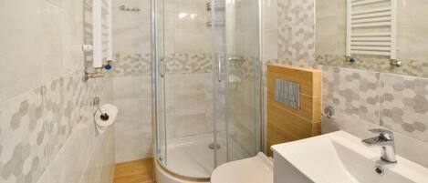 Un baño con ducha acristalada, inodoro y lavabo con espejo.