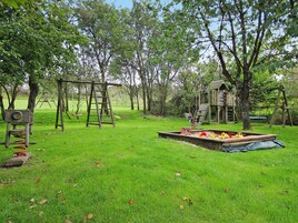 A playground with swings, a slide, and a small wooden structure.