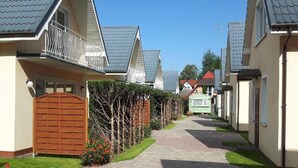 Une rue résidentielle bordée de maisons, avec un trottoir dallé et un portail en bois.