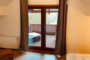 Enjoy a room with a sliding glass door leading to a balcony offering a view of lush greenery.