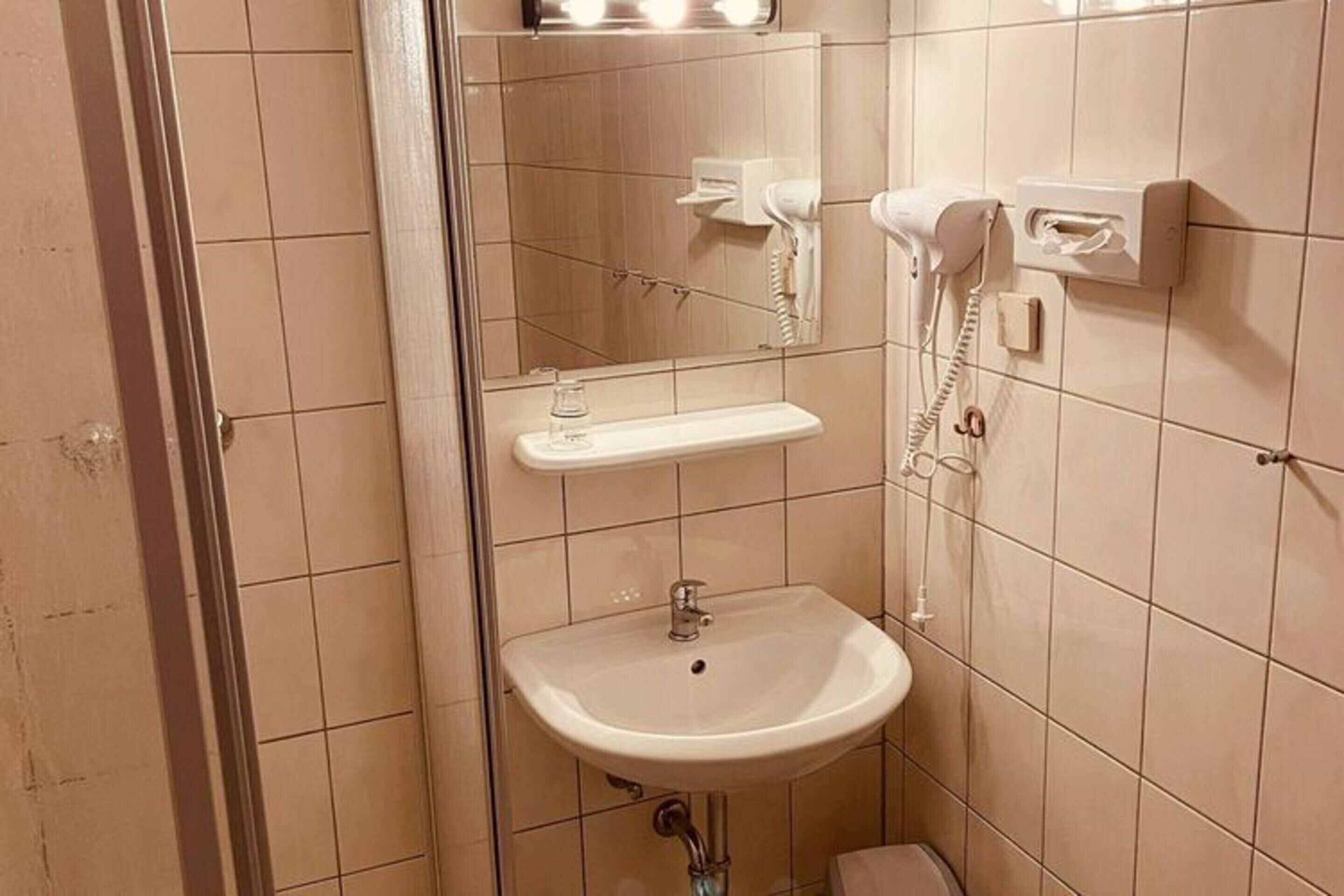 A small bathroom with a sink, a mirror, a hairdryer, and a telephone.