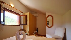 Habitación de hotel con cama, una silla, un espejo y ventana con vistas a zonas verdes.
