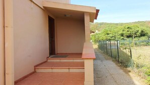Un edificio con techo plano, un pequeño porche con escalones y vistas a un paisaje verde.