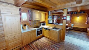 A cozy cabin-style kitchen with wooden cabinets, a stove, sink, and a dining area with a bench and table. - Chalet in Wildkogel Near Ski Slopes (Neukirchen am Grossvenediger)