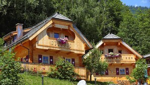 A wooden chalet with balconies, surrounded by greenery and a stone wall. - Chalet in Wildkogel Near Ski Slopes (Neukirchen am Grossvenediger)