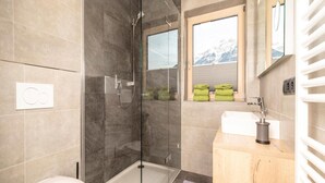 A modern bathroom with a glass-enclosed shower, a white toilet, and a wooden vanity with a sink. - Penthouse in Strass Near Zillertal Alps (Strass im Zillertal)