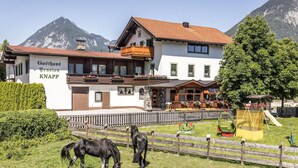 A hotel with a mountain backdrop, a fenced horse area, and a playground. - Penthouse in Strass Near Zillertal Alps (Strass im Zillertal)