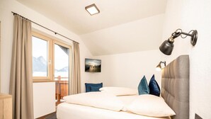 A bedroom with a bed, a window with curtains, a picture on the wall, and a bedside lamp. - Penthouse in Strass Near Zillertal Alps (Strass im Zillertal)