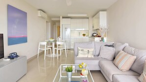 Ein modernes Wohnzimmer mit Sofa, Couchtisch und einem Essbereich mit Stühlen.