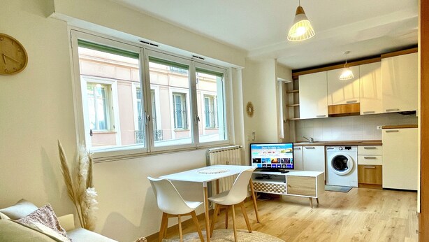 Un espacio habitable funcional con zona de comedor, lavadora y televisor.