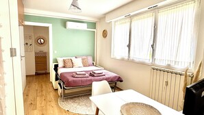 Un dormitorio con cama, mesita de noche y ventana con cortinas.