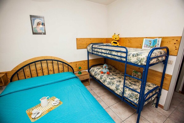 A bunk bed room with a blue bedspread, a wooden headboard, and a small table with a teapot and cups.